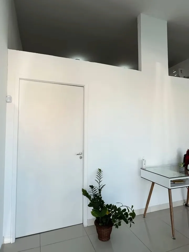 Recepção clara, com piso claro e um vaso de planta