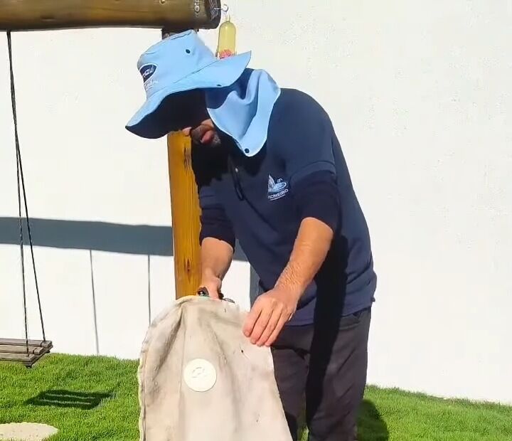 Luis Alberto uniformizado recolhendo a sujeira da piscina com o saco do filtro