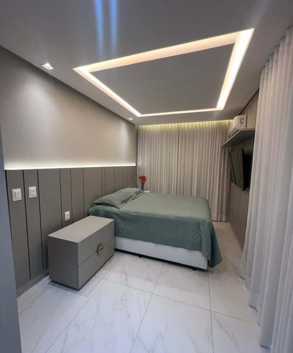 Quarto com painel estofado cinza, sanca iluminada e criado-mudo planejado