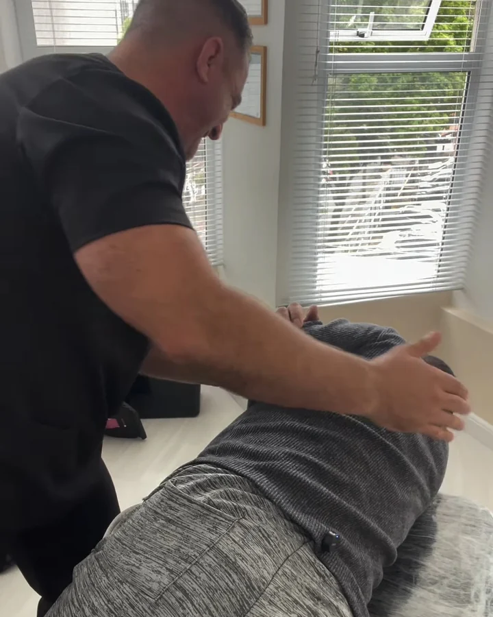 Vladimir com as mãos nas costas de um paciente deitado, aplicando um ajuste